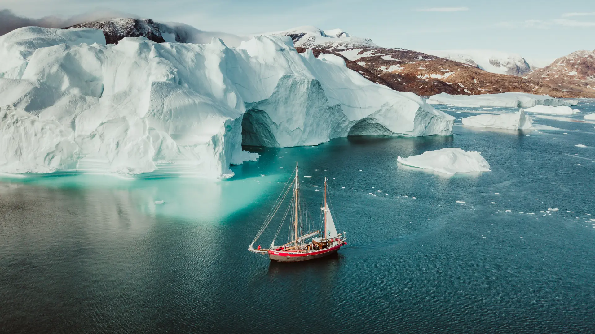 Iceberg and sailboat in a fjord